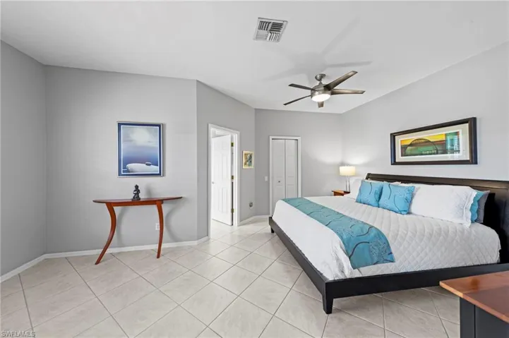 Bedroom with light tile patterned floors, ceiling fan, and a closet