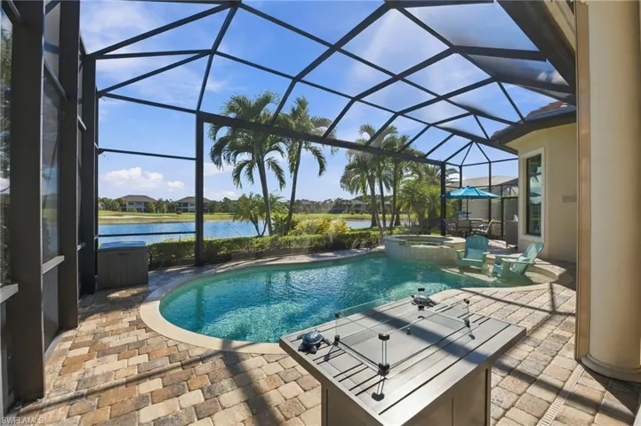 Screened lanai featuring a paver deck, built-in swimming pool, integrated spillover spa, and water frontage