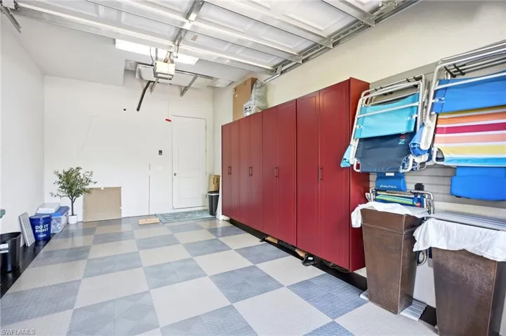 Garage featuring checkerboard-patterned floor tiles, wall-mounted storage cabinetry, and integrated slat-wall organization system