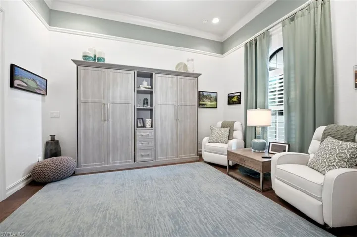 Custom built-in cabinetry with integrated shelving and drawers, high ceilings with crown molding, and an arched window featuring plantation shutters
