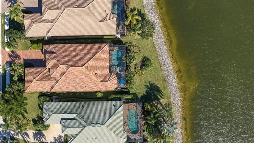 Waterfront properties featuring screened-in pool enclosures, tile roofing, and paved driveways