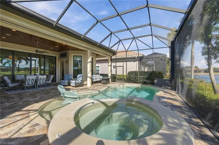 Screen-enclosed patio featuring a paver deck, integrated spa, and swimming pool with a wood-finish ceiling accent on the covered lanai