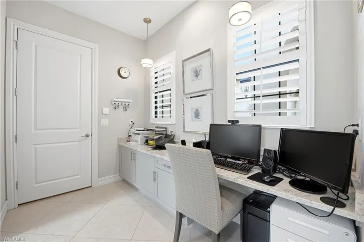 Built-in cabinetry with stone-finish countertops, tile flooring, plantation shutters, and pendant lighting