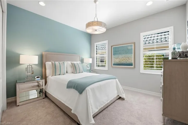Bedroom featuring neutral carpeting, an accent wall, recessed lighting, a decorative drum chandelier, and plantation shutters