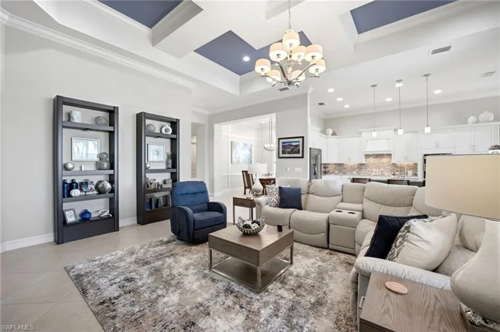 Coffered ceiling with accent color, chandelier, built-in shelving, tile flooring, and recessed lighting