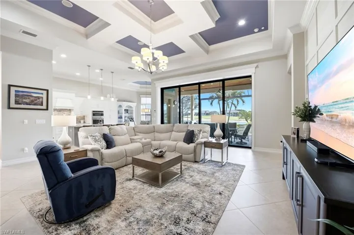 Coffered ceiling with recessed lighting, large-format tile flooring, and floor-to-ceiling sliding glass doors opening to the exterior