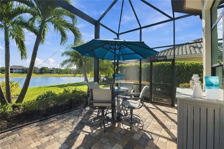 Screened-in lanai with paver flooring, tall metal framing, and direct water exposure