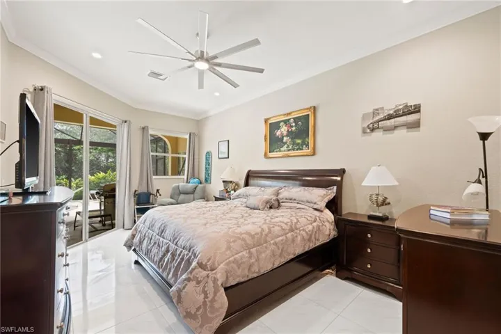 Tiled bedroom with ceiling fan, crown molding, and access to exterior