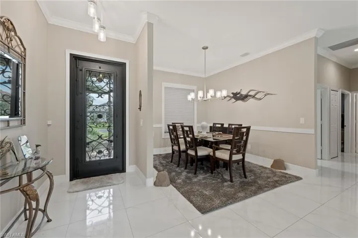Tiled entryway with crown molding and an inviting chandelier