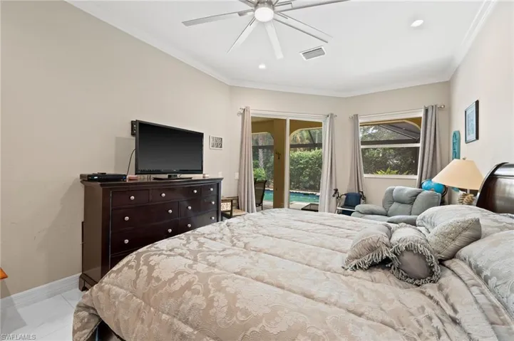 Tiled bedroom featuring ceiling fan, access to exterior, and ornamental molding