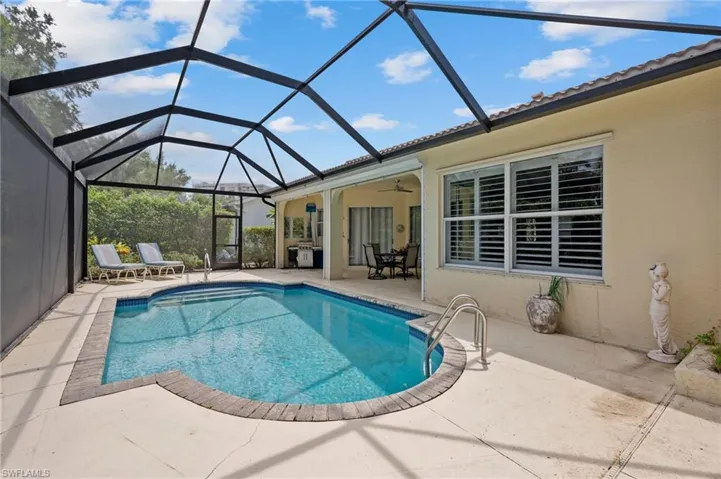View of pool with a patio, glass enclosure, and ceiling fan