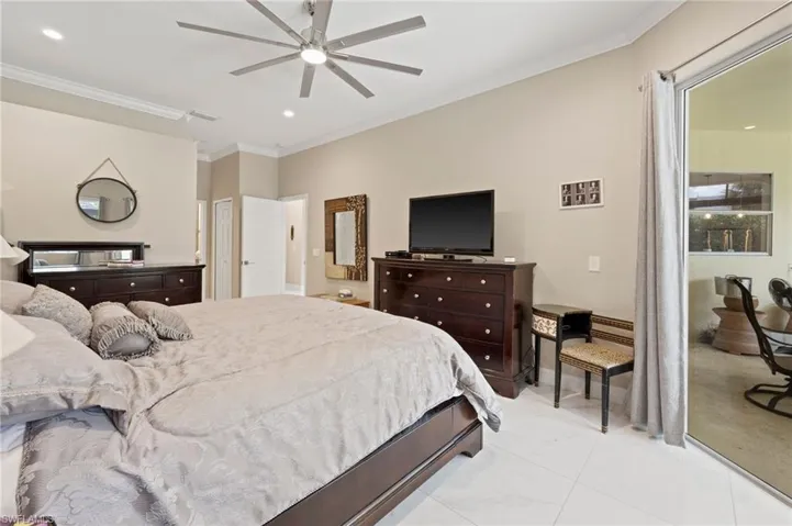 Tiled bedroom featuring ceiling fan and ornamental molding