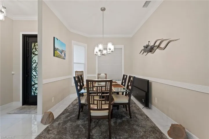 Dining space with light tile patterned floors, crown molding, and a chandelier