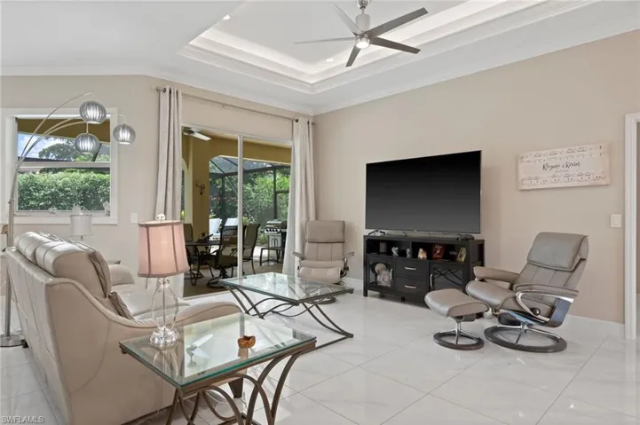 Living room featuring plenty of natural light, a raised ceiling, ornamental molding, and light tile patterned floors