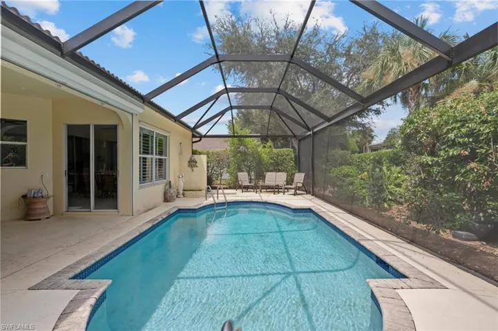 View of pool featuring glass enclosure and a patio