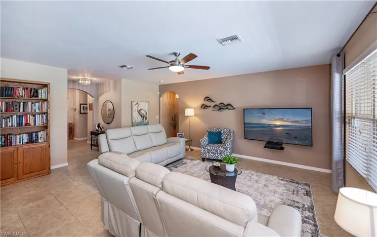 Living room with arched walkways, ceiling fan, and light tile patterned floors
