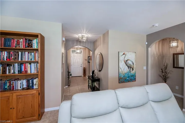 Living area with arched walkways, light tile patterned floors, and a chandelier