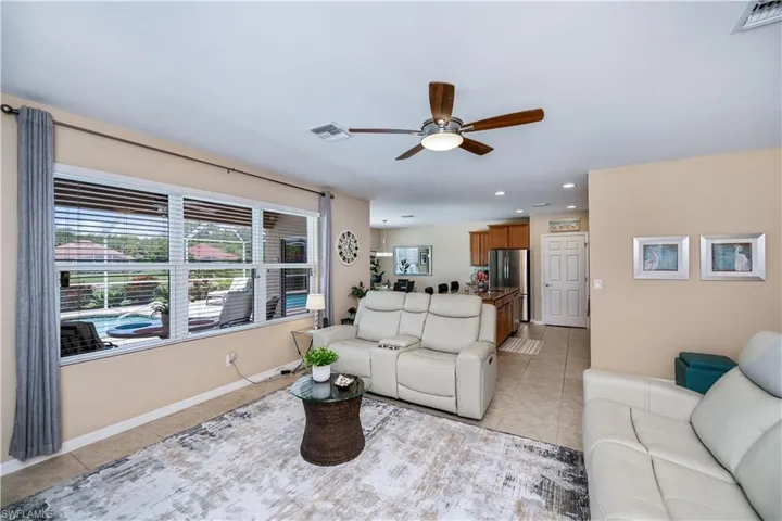 Living area with light tile patterned floors, a ceiling fan, and recessed lighting