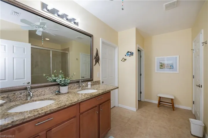 Bathroom featuring tile patterned flooring, vanity, a shower with door, and ceiling fan