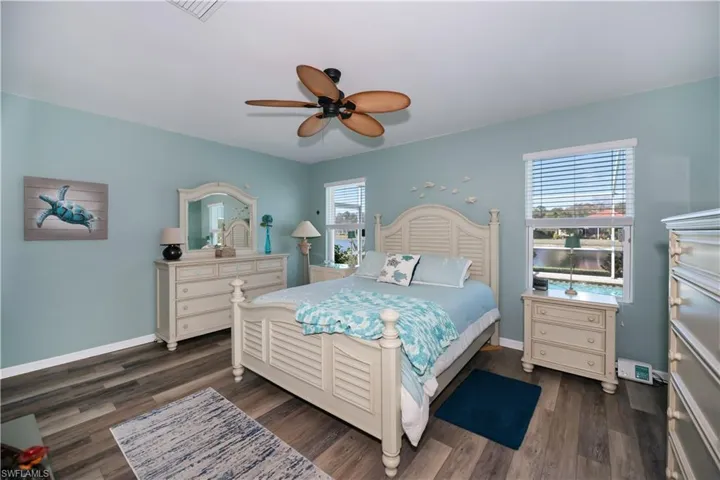 Bedroom with ceiling fan, dark wood-type flooring, and multiple windows