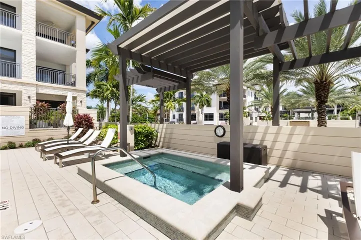 View of pool with a hot tub, a patio area, and a pergola