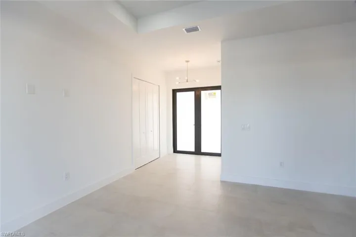 Empty room with french doors and a chandelier