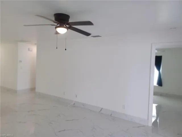Empty room with ceiling fan and light marble finish floors
