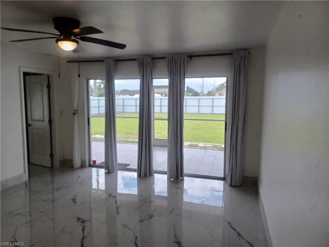 Empty room with light marble finish flooring, ceiling fan, and a water view