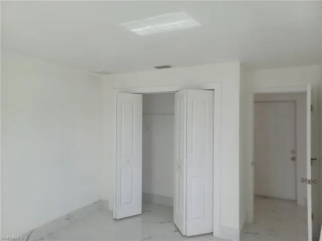 Unfurnished bedroom with light marble finish flooring and a closet