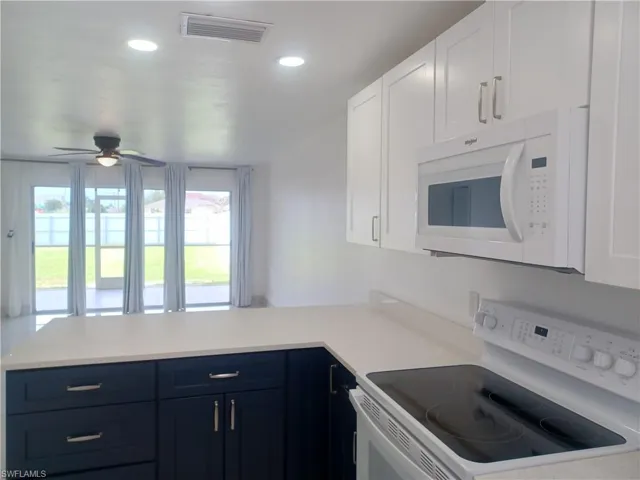 Kitchen featuring white appliances, a peninsula, plenty of natural light, light countertops, and recessed lighting