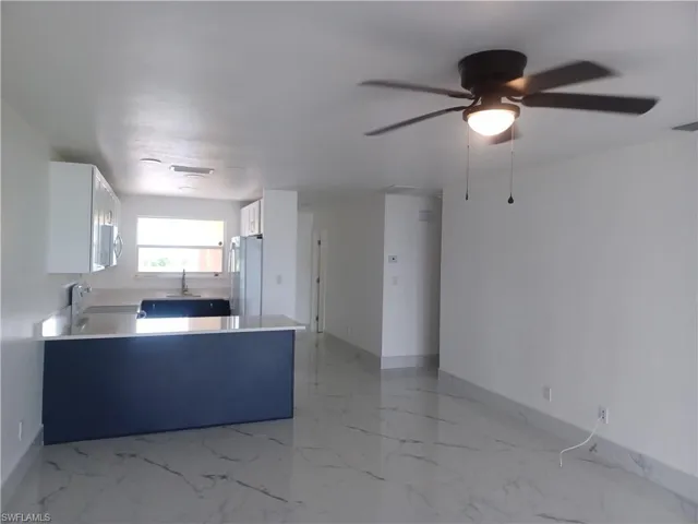 Kitchen featuring freestanding refrigerator, range, a peninsula, and white cabinetry