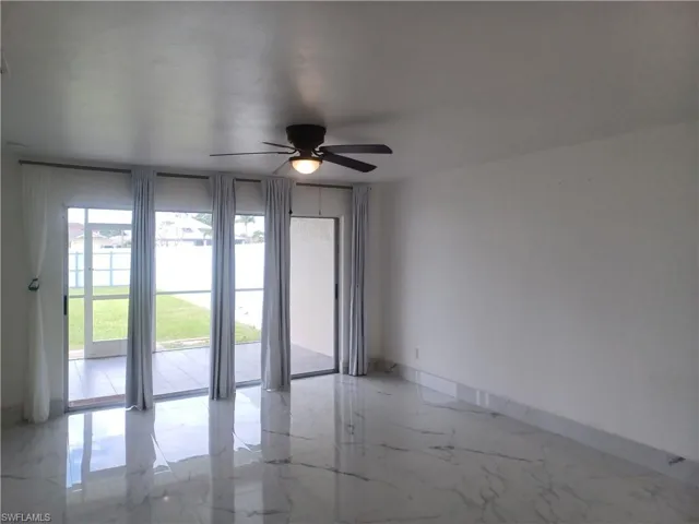 Unfurnished room featuring a ceiling fan and light marble finish flooring