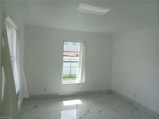 Unfurnished room featuring marble finish flooring and baseboards