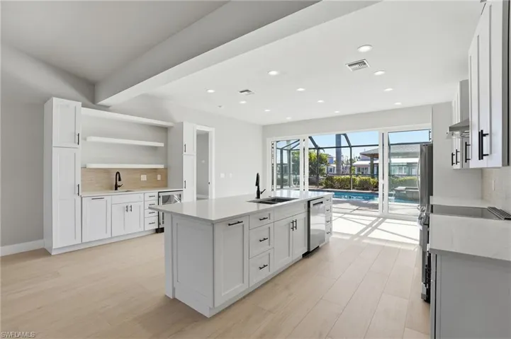 Kitchen with a sunroom, decorative backsplash, white cabinetry, light stone counters, and recessed lighting - Virtually Edited Image