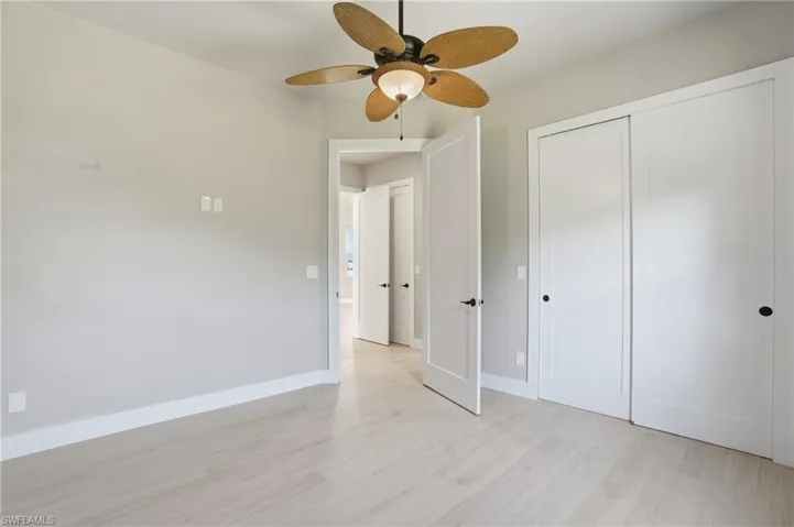 Unfurnished bedroom with light wood-type flooring, ceiling fan, and a closet - Virtually Edited Image