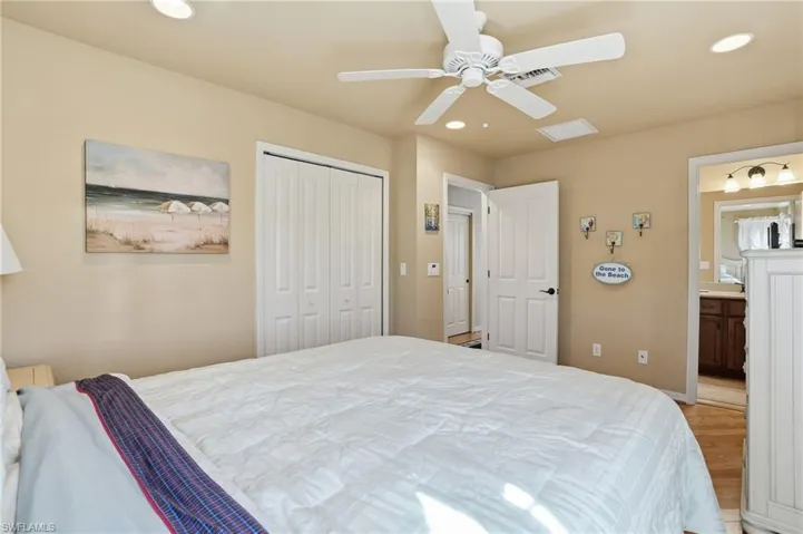 Bedroom with recessed lighting, a closet, a ceiling fan, ensuite bathroom, and wood finished floors - Virtually Edited Image