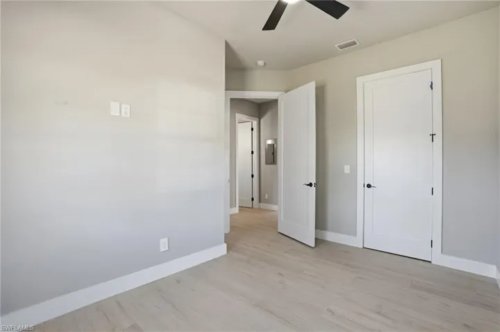 Unfurnished bedroom with light wood finished floors and a ceiling fan - Virtually Edited Image