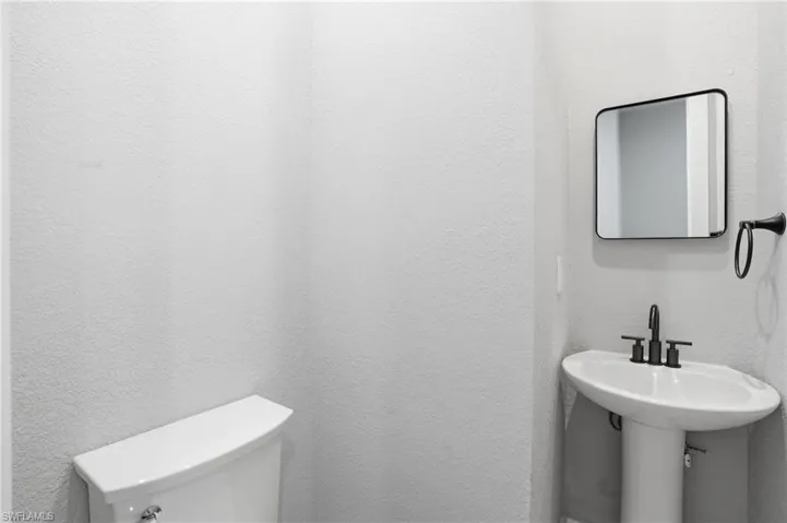 Bathroom featuring toilet and a textured wall - Virtually Edited Image
