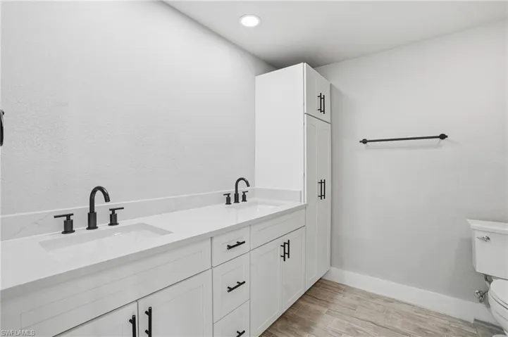 Full bath featuring double vanity, light wood finished floors, and recessed lighting - Virtually Edited Image