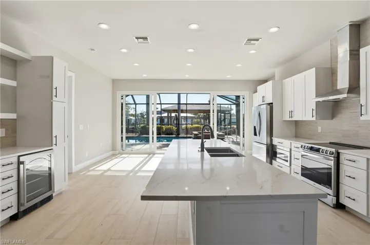 Kitchen with tasteful backsplash, white cabinets, stainless steel appliances, light stone counters, and recessed lighting - Virtually Edited Image