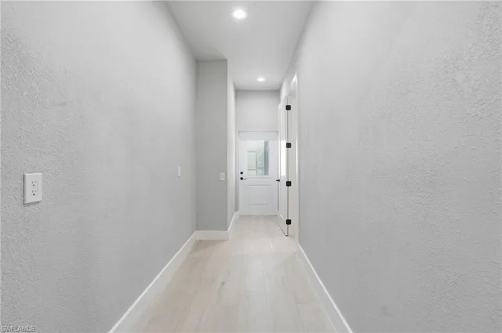 Hall featuring recessed lighting, a textured wall, and light wood-type flooring - Virtually Edited Image