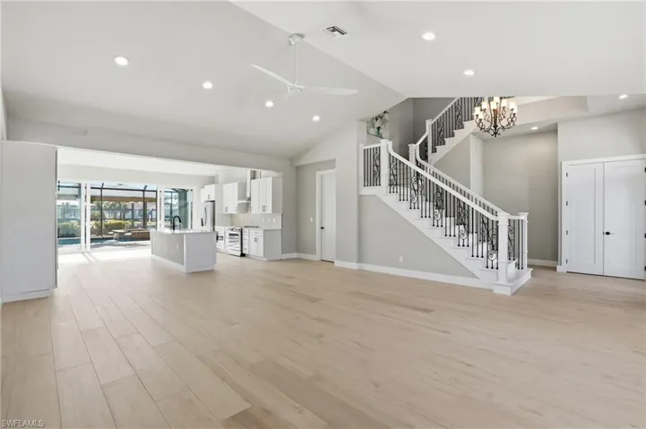 Unfurnished living room with a ceiling fan, light wood-type flooring, vaulted ceiling, and hanging lights - Virtually Edited Image