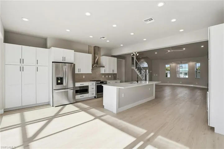 Kitchen with stainless steel appliances, white cabinetry, open floor plan, tasteful backsplash, and recessed lighting - Virtually Edited Image