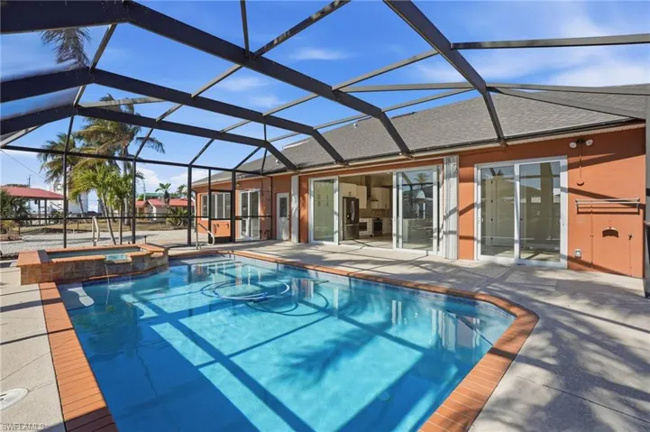 Combined pool / hot tub with glass enclosure, a sunroom, and a patio - Virtually Edited Image