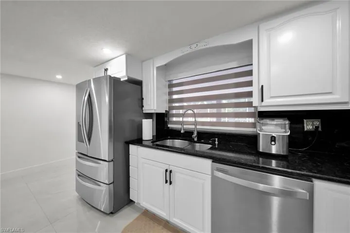 Kitchen featuring white cabinetry, dark stone countertops, stainless steel appliances, recessed lighting, and tile flooring