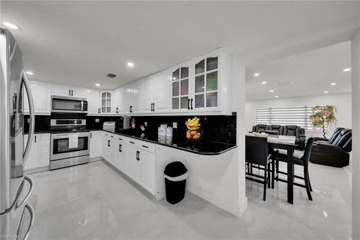 Kitchen featuring white cabinetry, dark countertops, stainless steel appliances, and recessed lighting