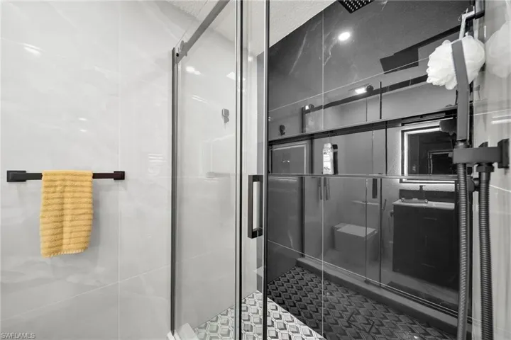 Glass-enclosed shower with matte black fixtures and a rain shower head