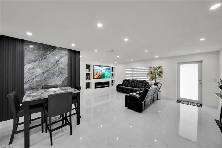 Open-concept living area featuring high-gloss tile flooring, recessed lighting, and a contemporary accent wall with vertical paneling and a central stone-finish section