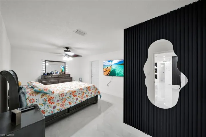 Bedroom featuring a contemporary black slatted accent wall with an organic-shaped mirror
