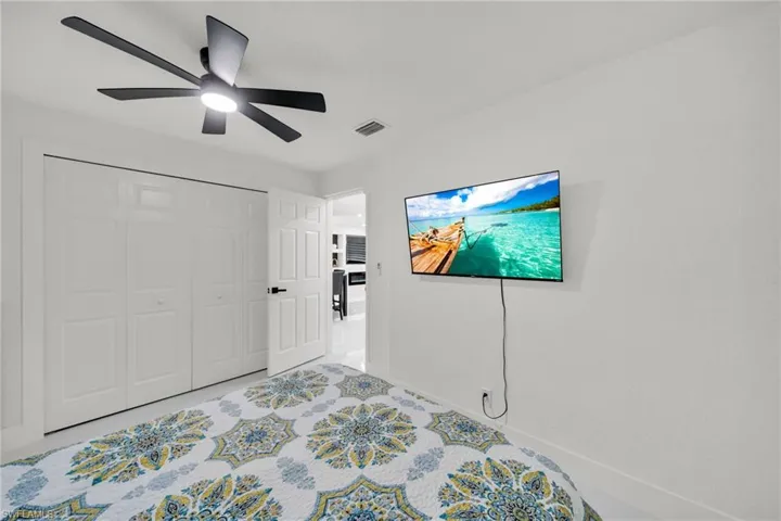 White interior space featuring a ceiling fan with integrated lighting, bi-fold closet doors, a paneled interior door with dark hardware, and bright white walls